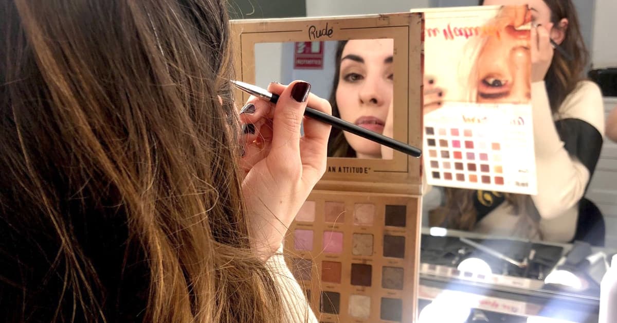 Mujer aplicando maquillaje frente al espejo durante un curso de automaquillaje en Madrid en Mak School.